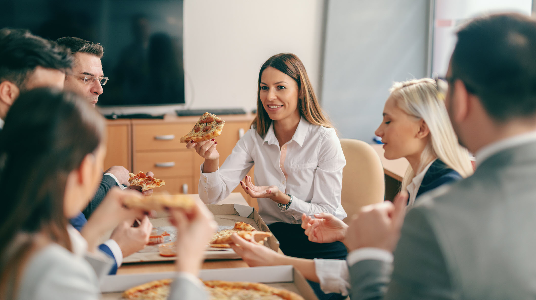 People in confenrece room eating pizza - Wide